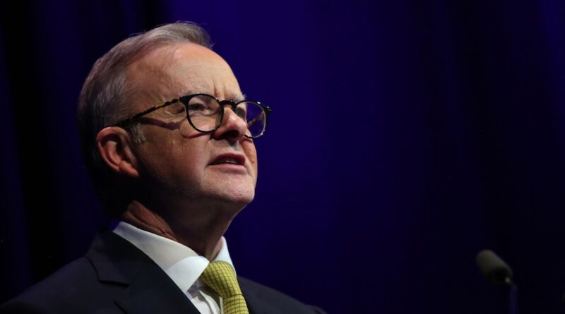 Anthony Albanese looks out at the audience, wearing a yellow tie and suit